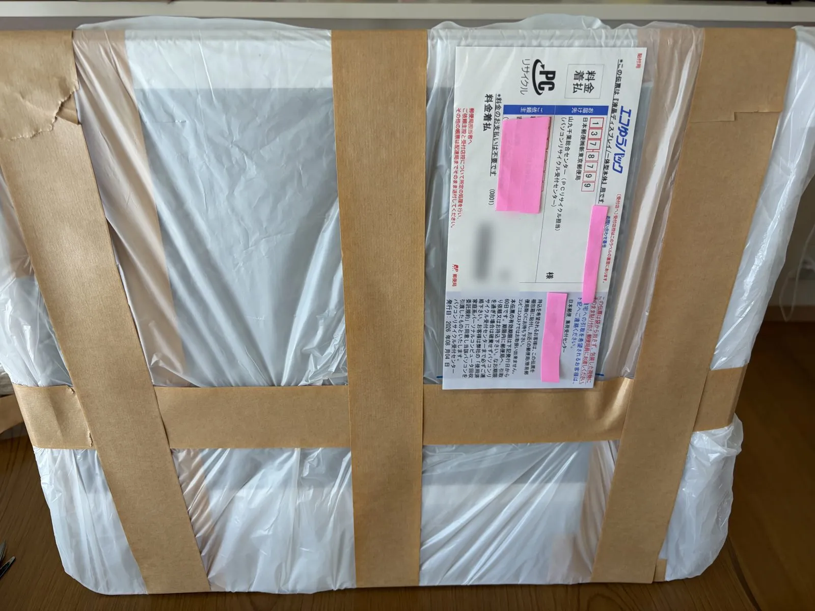ビニール袋で梱包し伝票を貼ったパソコン。発送準備完了
